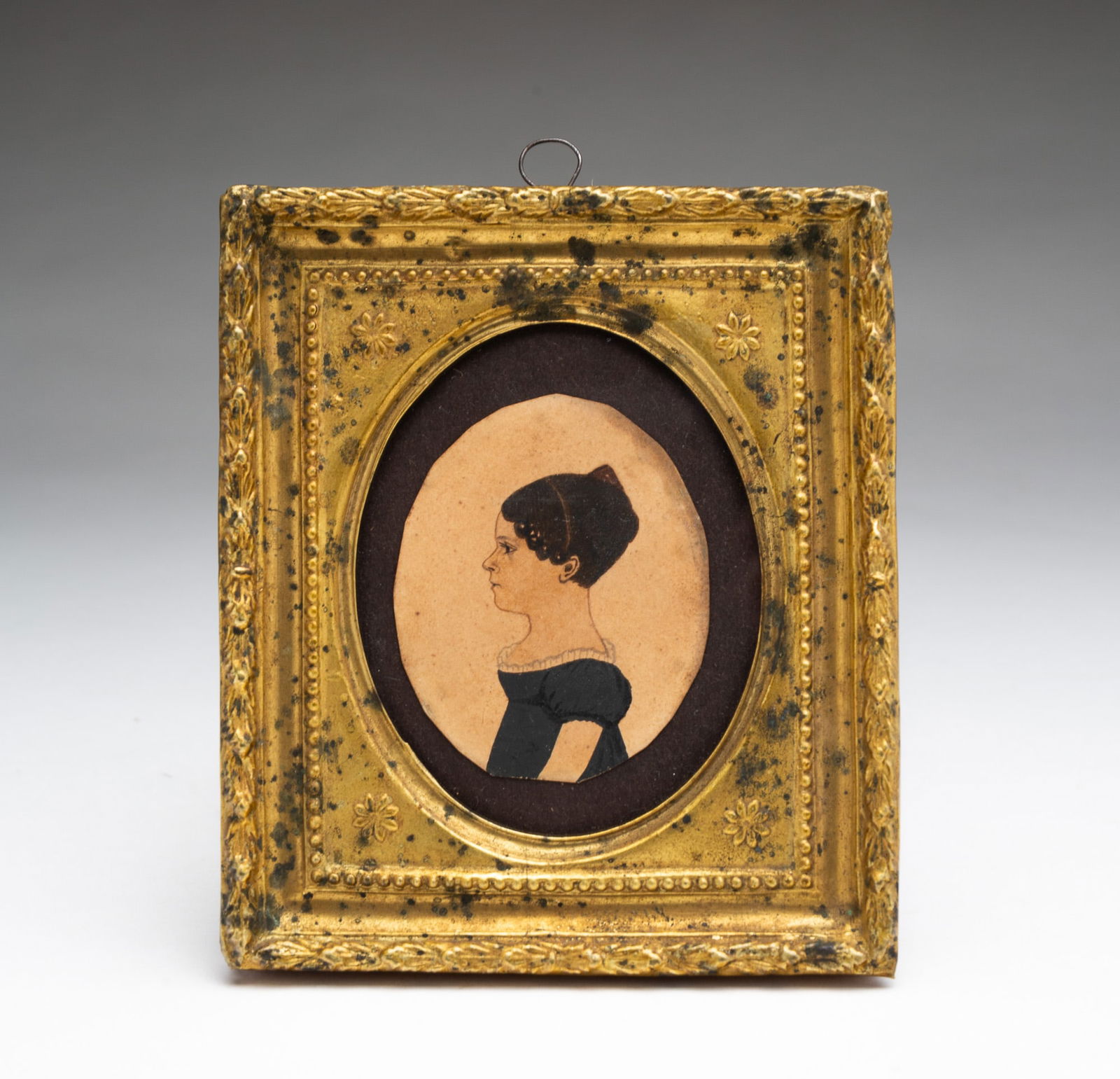 MINIATURE AMERICAN SCHOOL WATERCOLOR PORTRAIT OF A GIRL.: Ca. 1830. Profile portrait of a young girl, facing left, having dark brown hair worn up with tortoise shell comb and headband with tight curls framing her face, wearing a black dress with white lace t