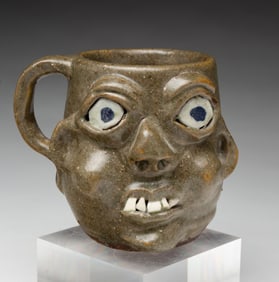 GRACE NELL HEWELL (GILLSVILLE, GEORGIA, 1933-2016) FOLK ART GROTESQUE FACE MUG, DATED 1998.