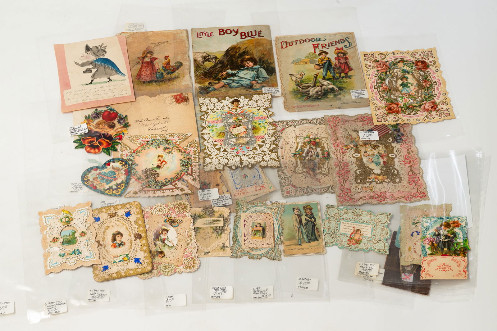 COLLECTION OF TWENTY-FIVE VICTORIAN VALENTINES AND THREE CLOTH CHILDREN'S BOOKS.: American, 19th-20th Century. Approximately twenty-five valentines of various forms, some with handwritten notes, in protective plastic sheets, plus three cloth children's books. 3"h. to 7"h.Provenance
