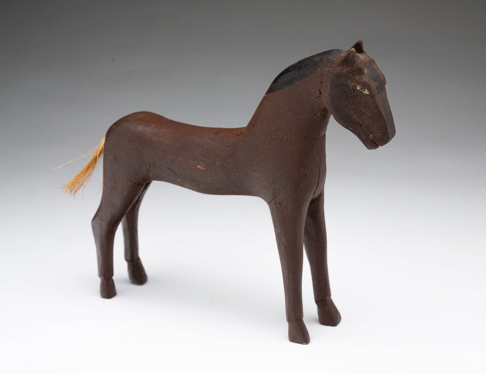 AMERICAN FOLK ART CARVED AND PAINTED WOOD HORSE.: First half 20th Century. Carved wood horse in original brown paint with painted eyes and mane and horsehair tail. 7"h.Provenance: From the Collection of Peggy McClard & Randy Segotta (Weare, New Hamps