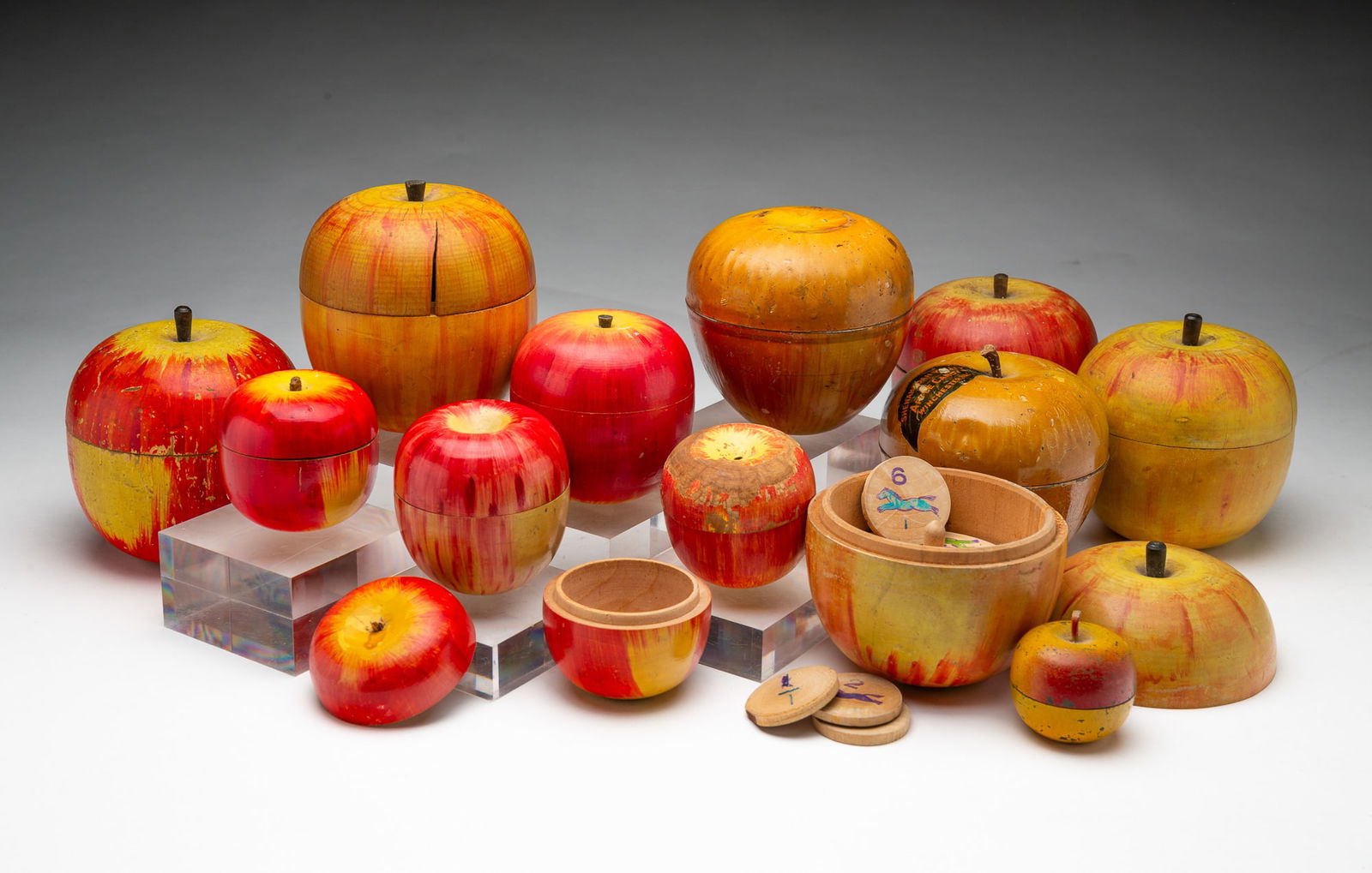COLLECTION OF THIRTEEN FOLK ART APPLE CONTAINERS AND GAMES.: American and Japanese, Early-mid 20th Century. Wood and tin. Assorted apple forms in two parts in several sizes, including five Japanese wooden apples with race horse games inside, one with a miniatur