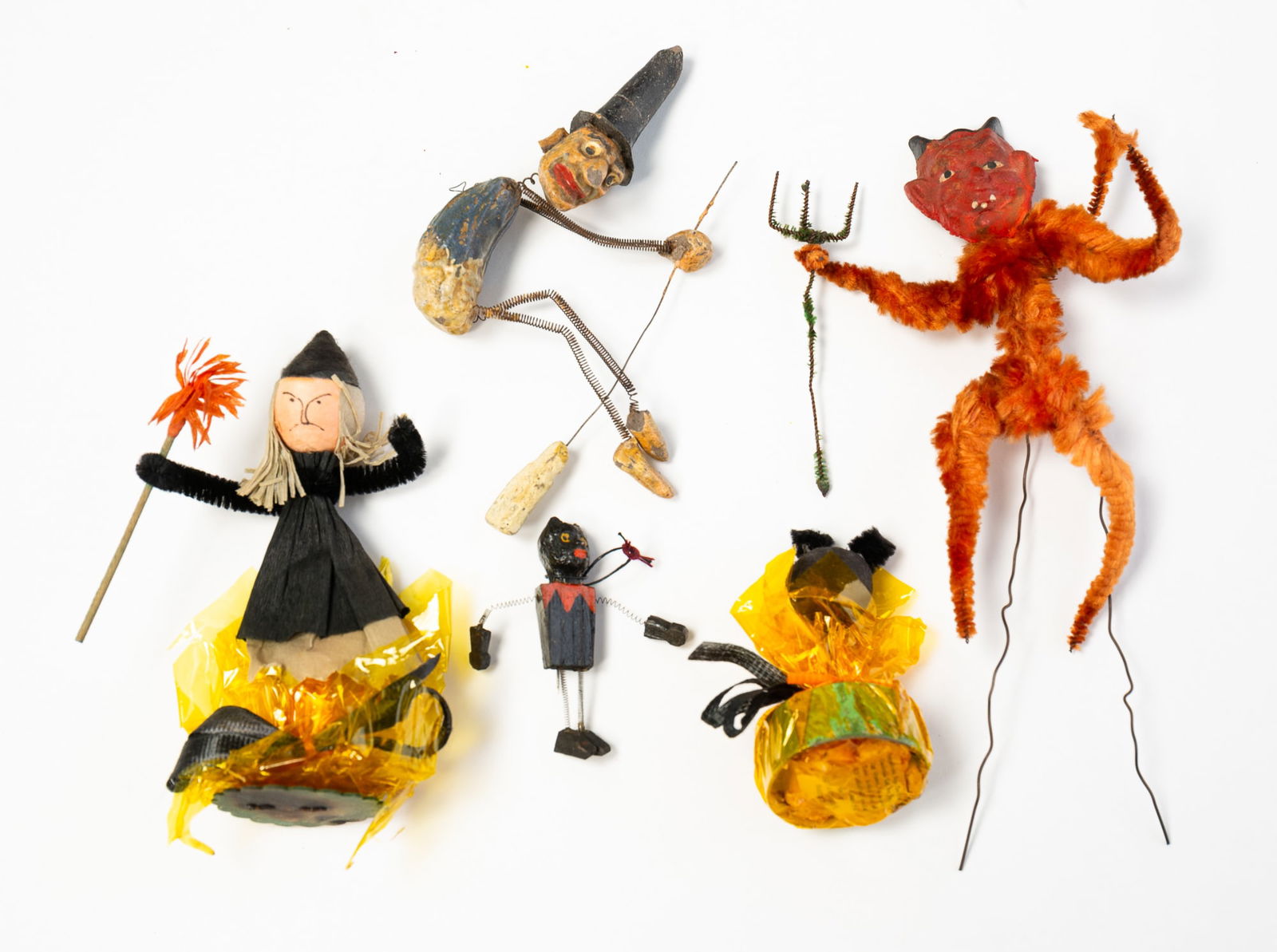 COLLECTION OF FIVE HALLOWEEN DECORATIONS.: American, 20th Century. Comprising a carved and painted witch riding a broom with spring arms and legs, a carved and painted black cat with spring arms and legs, a papier-mache and chenille Krampus, a