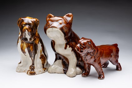 THREE AMERICAN BUFF CLAY GLAZED DOGS.
