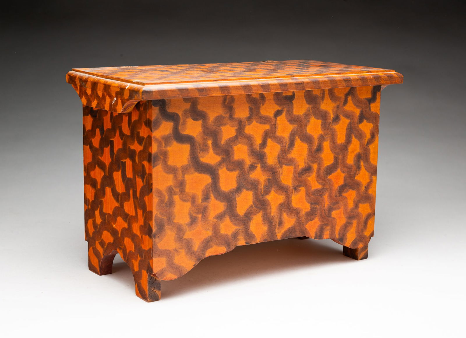 MINIATURE C.F HOPF (KINNEBUNK, MAINE) PAINT-DECORATED PINE BLANKET CHEST.: Late 20th Century. Lid with routed edge and shaped end battens, staple hinges, bootjack ends, shape apron and orange paint with brown-black basket weave pattern. Label inside lid. 8"h. 12"w. 5.75"d.Pr