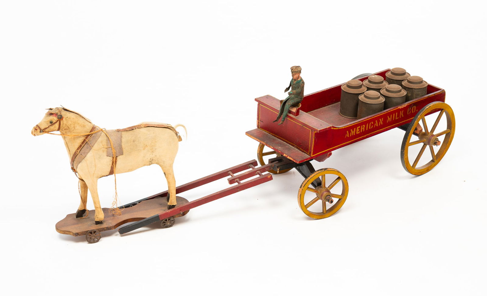 AMERICAN MILK CO. TOY BUCKBOARD WAGON WITH HORSE DRIVER AND MILK CANS.: Ca. 1900. Wagon with original red, black and yellow paint, cloth covered horse pull toy, horse hair mane and tail, oil cloth harness on a base with cast iron wheel. Mismatched painted tin driver and s