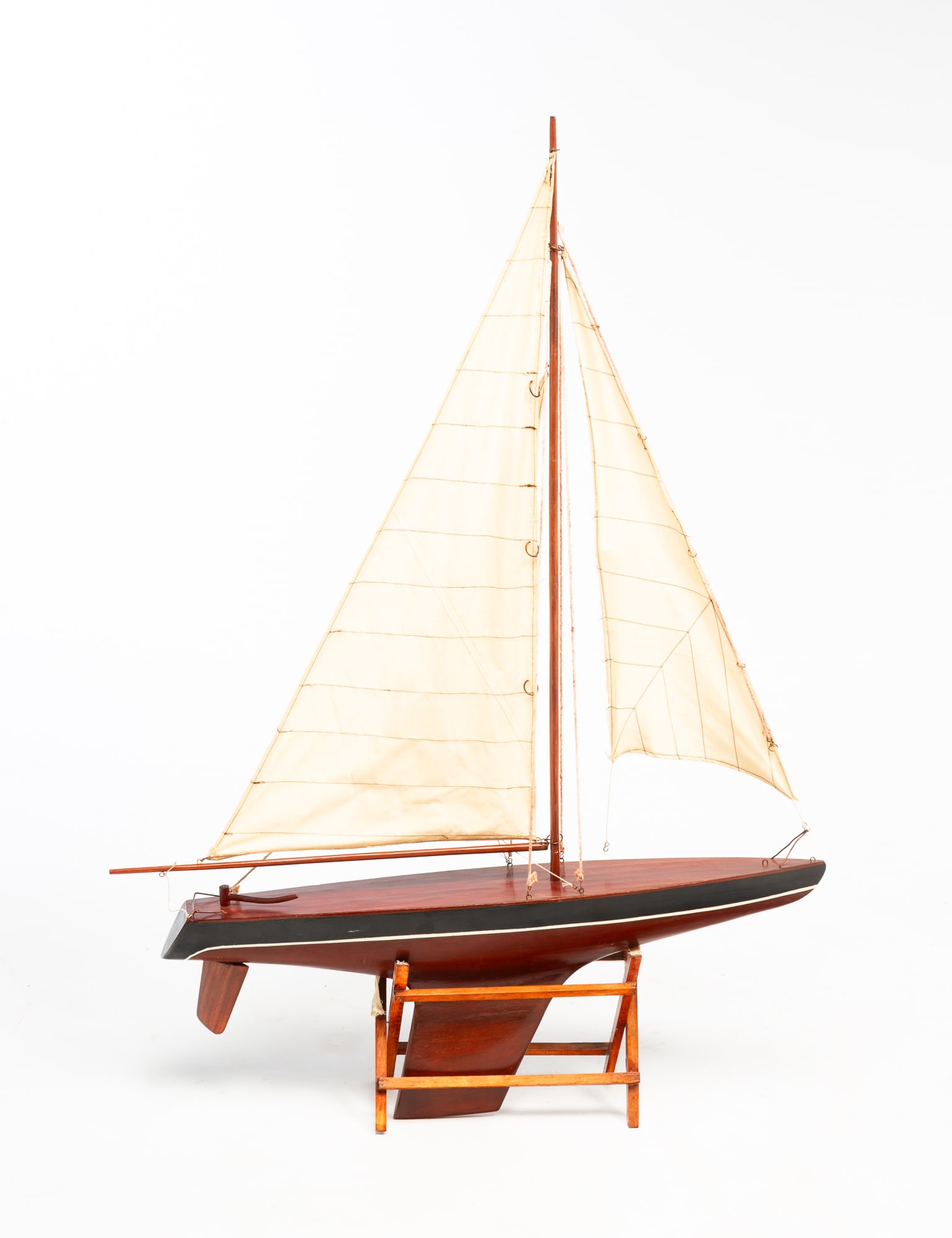 AMERICAN POND SAILER MODEL.: 20th century. Scale model of a wooden boat having three stitched linen sails, with stand. Boat, 40"h. 28"w.Provenance: From the Lifetime Collection of Ronald & Kathy Wright (Willoughby, Ohio). PLEASE