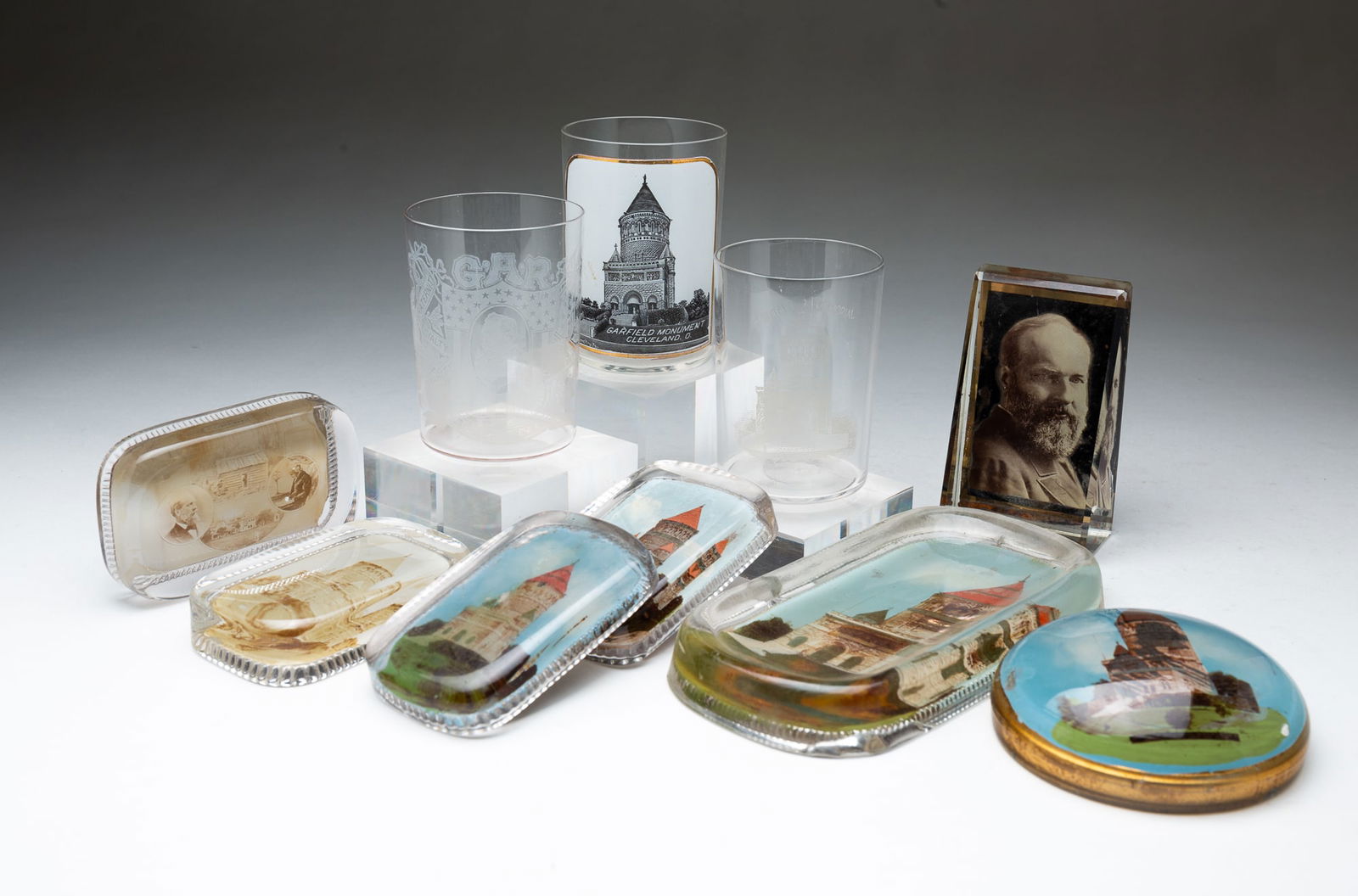 TEN PRESIDENT GARFIELD RELATED ITEMS, INCL. PAPERWEIGHTS.: American, late 19th Century. Five are paperweights of the memorial, a paperweight of Garfield birth home, a paper weight with Portrait of Garfield, three tumblers: two of the Memorial and G.A.R. Souve