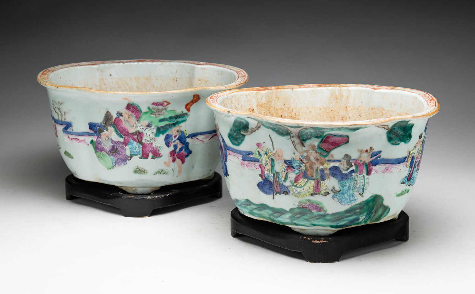 PAIR OF CHINESE EXPORT PORCELAIN FAMILE ROSE JARDINIÈRES.: 19th Century. Matching pair with famile rose decoration, shaped sides, resting on four feet with wooden stands. 6.5"h. 10.75"w. From the lifetime collection of the late Audree and Bryce Chase (Port Ro