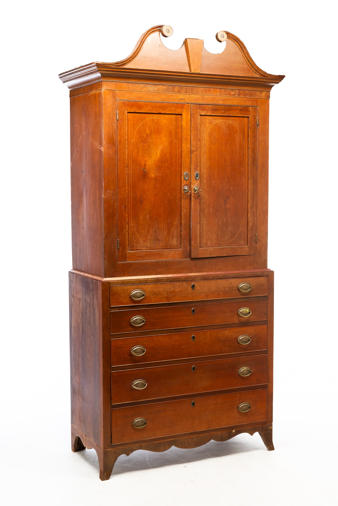 AMERICAN HEPPLEWHITE CHERRY AND STRING-INLAID LINEN PRESS.: Maryland or Virginia, ca. 1800. In two pieces. The top having a scrolled front cornice over two doors, opening to an interior of fixed shelves, the lower case with mahogany veneer ends, five full-widt