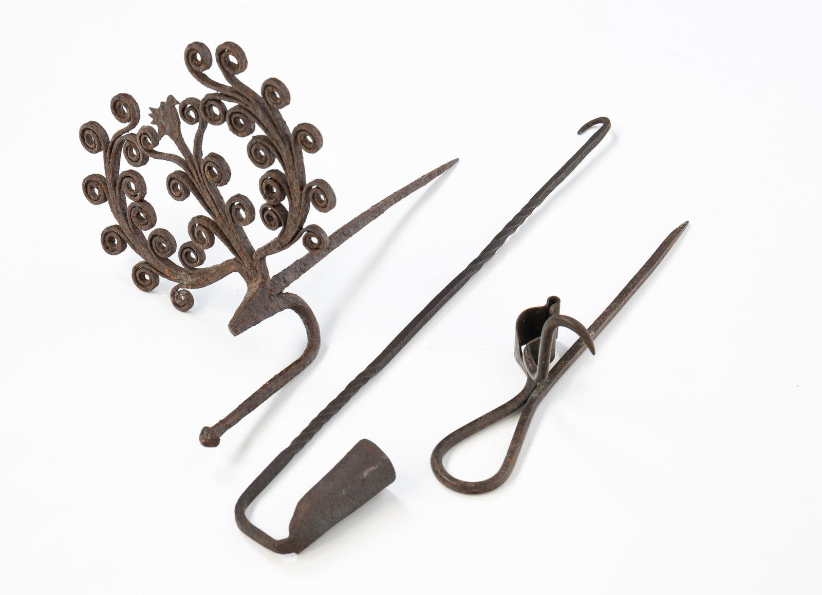 THREE AMERICAN IRON LIGHTING DEVICES.: 19th Century. Sticking tommy, 3"h. 10.5"l. Scrolled sticking tommy with hook, 7"h. 11"w. Hanging single candle holder, 16"h.Provenance: From the Lifetime Collection of the late Deb Fisher (Lebanon,