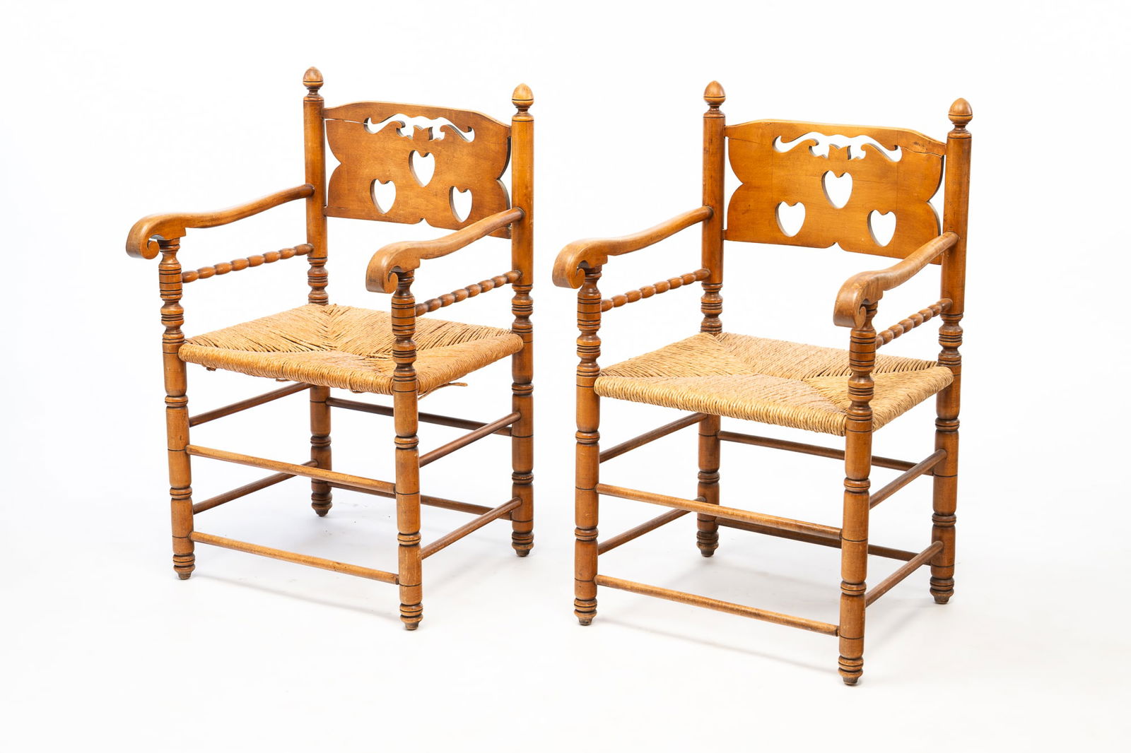 PAIR OF AMERICAN WILLIAM AND MARY STYLE MAPLE ARMCHAIRS.: 20th Century. Each having a backsplat with cutout hearts flanked by turned stiles with acorn finials continuing to scrolled arms above rush seats and rising on ring-turned legs joined by double-box
