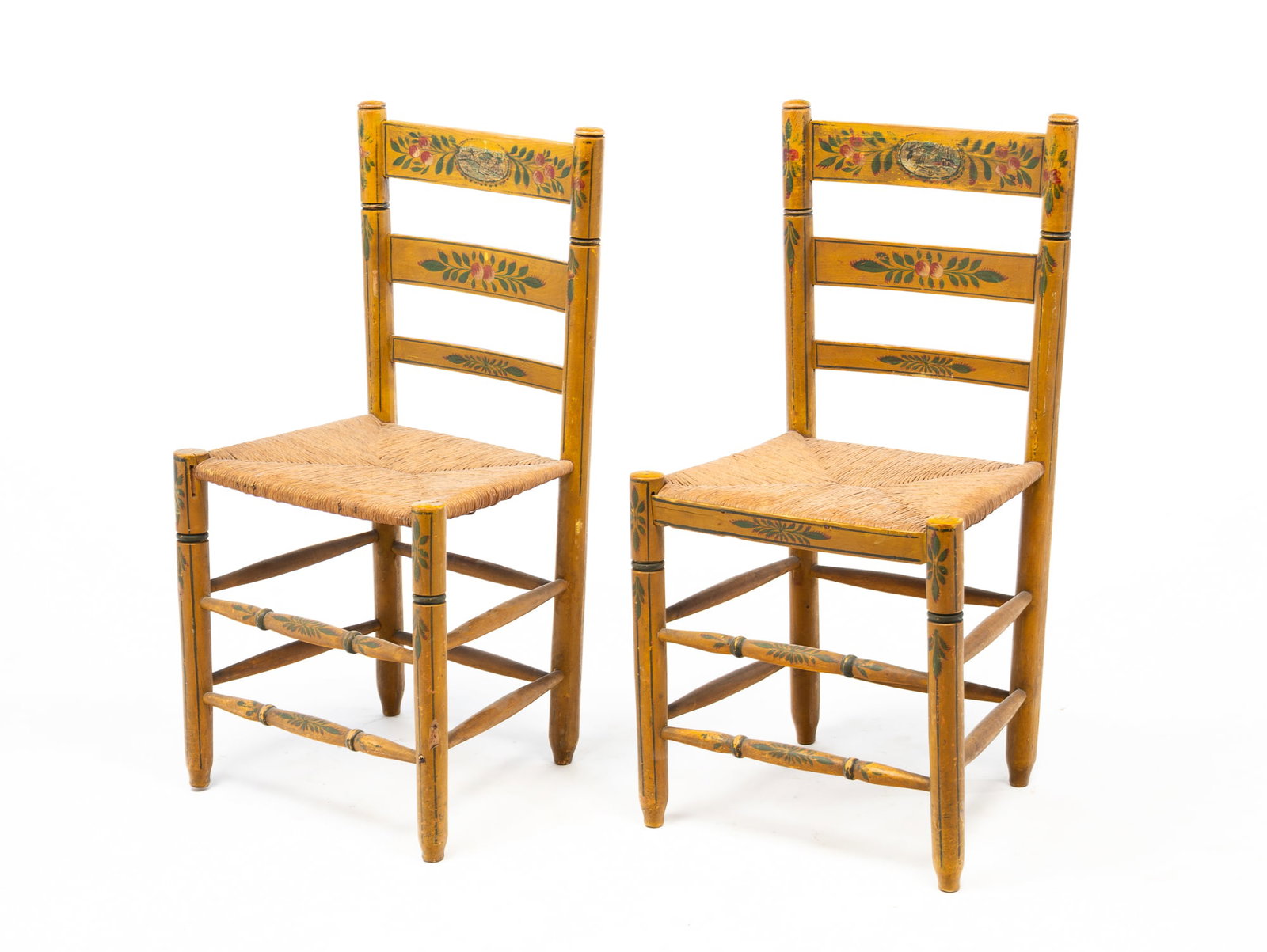 PAIR OF EUROPEAN POLYCHROME-DECORATED LADDERBACK SIDE CHAIRS.: 19th Century. Mixed woods. In yellow paint with foliate and fruit motifs throughout and landscape vignettes to crest rails. Each with three back slats flanked by turned stiles continuing to a rush sea