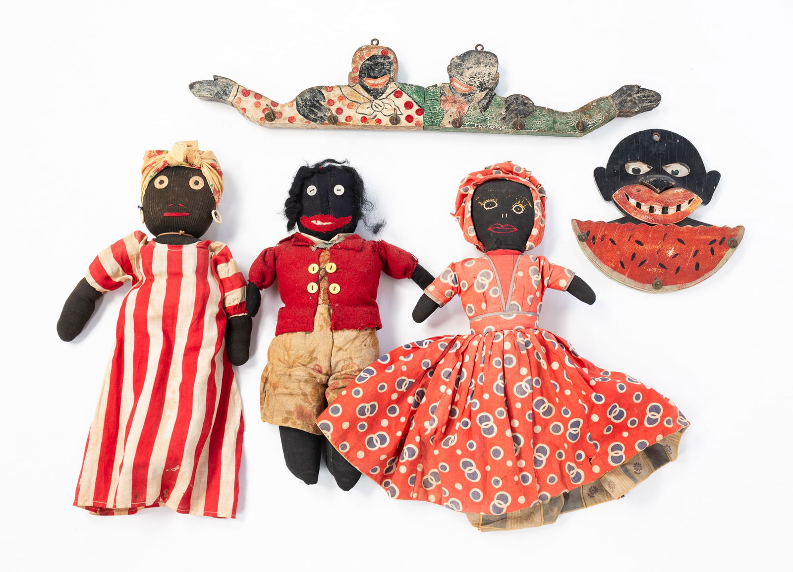 GROUP OF BLACK AMERICANA.: Early 20th Century. Two painted wood wall hanging hooks: a smiling face eating watermelon, 7.25"h. and a husband and wife with their arms intertwined and mounted with hooks, 4"h. 21"w. And three