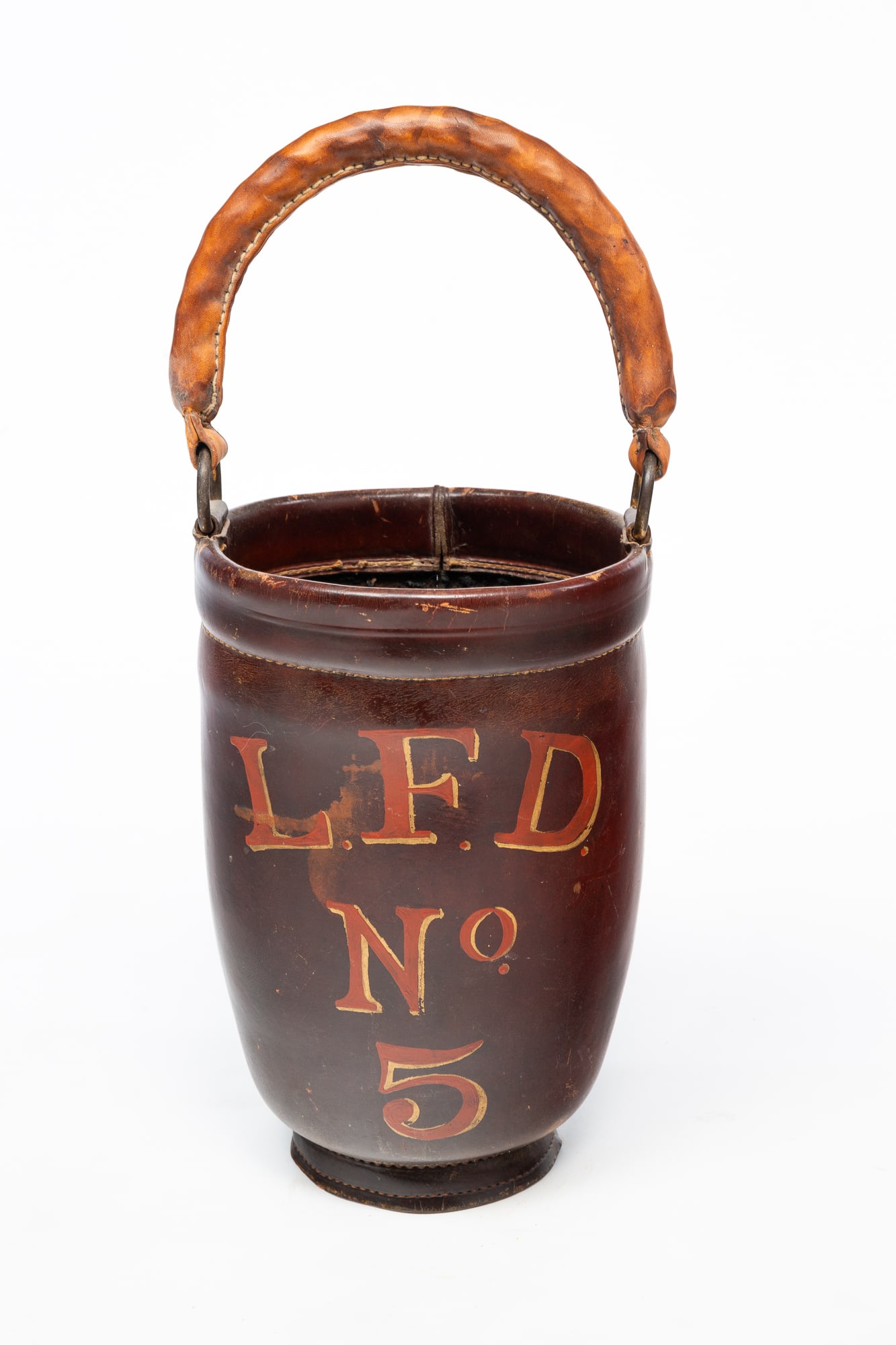 AMERICAN PAINTED LEATHER FIRE BUCKET.: 19th Century. Brown leather bucket with brown leather swing handled, painted with "L.F.D. No. 5" in orange lettering shaded in yellow. With handle, 20''h. 8.5"d.Provenance: From the Lifetime
