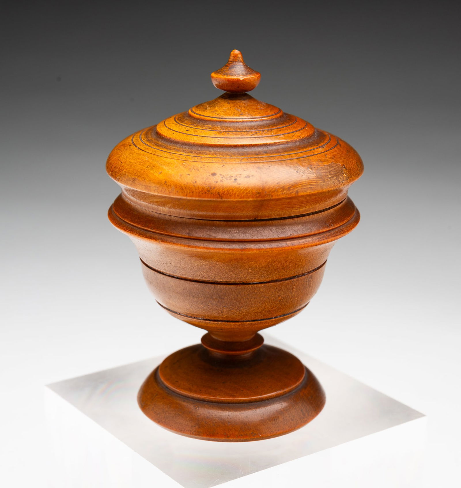 DIMINUTIVE OHIO PEASEWARE LIDDED JAR.: American, 19th Century. Lid with turned urn finial, tapered body with incised banding, and a ringed pedestal foot. 4"h.