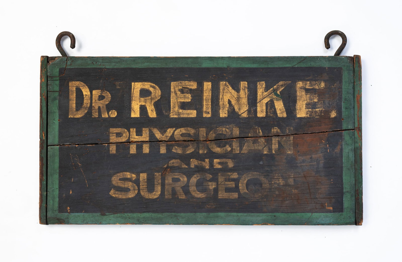 "DR. REINKE PHYSICIAN AND SURGEON" PAINTED AND PARCEL-GILT DOUBLE-SIDED TRADE SIGN.: American, late 19th Century. Pine. Breadboard ends, iron hooks, painted green border, black background and gold lettering. "DR. REINKE, PHYSICIAN AND SURGEON". 11"h. 21"w.