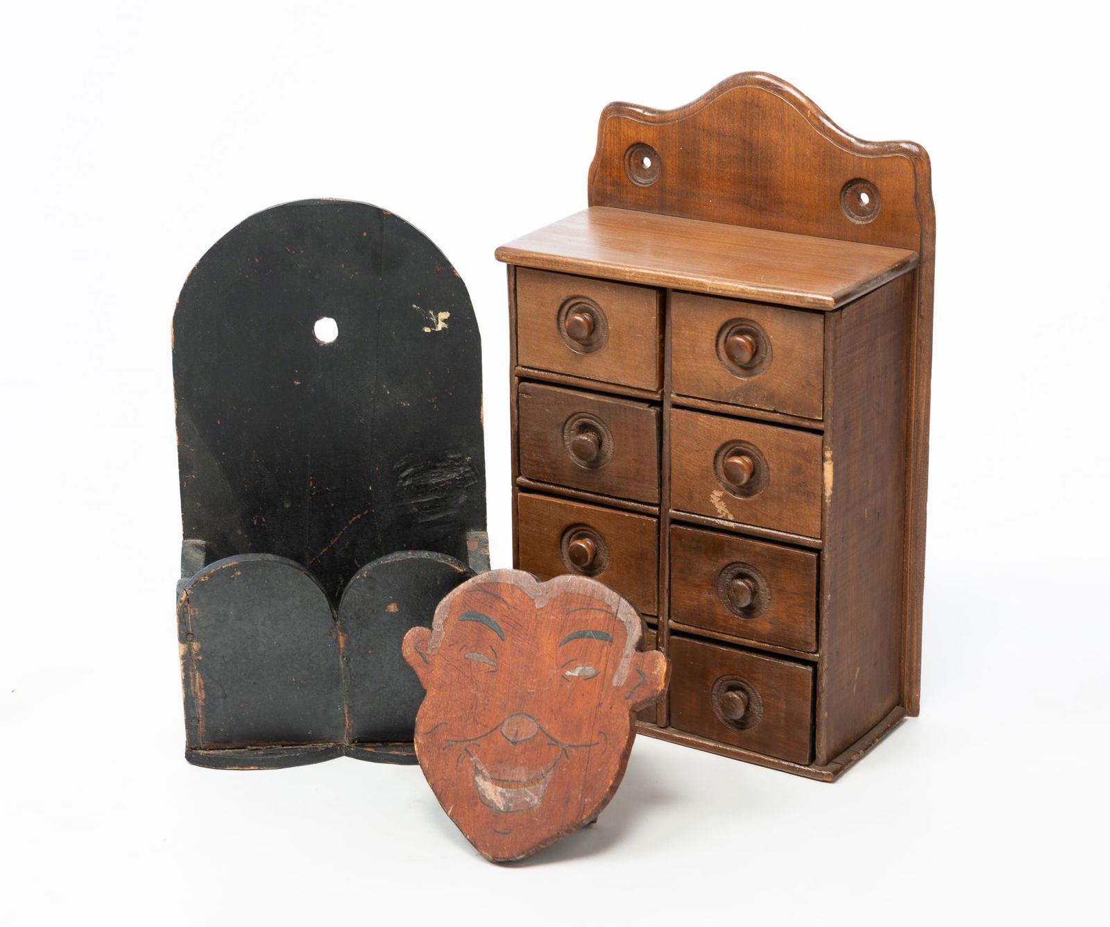 THREE AMERICAN WOODENWARE ITEMS.: Late 19th-20th Century. Pine eight-drawer spice cabinet with shaped crest and recessed turned knobs, 16.5"h. 10"w .5"d. Wall hanging broom holder with folksy painted face shaped front, 7?h. 6.75"w.
