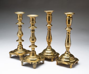 TWO PAIRS OF EASTERN EUROPEAN CAST BRASS CANDLESTICKS.