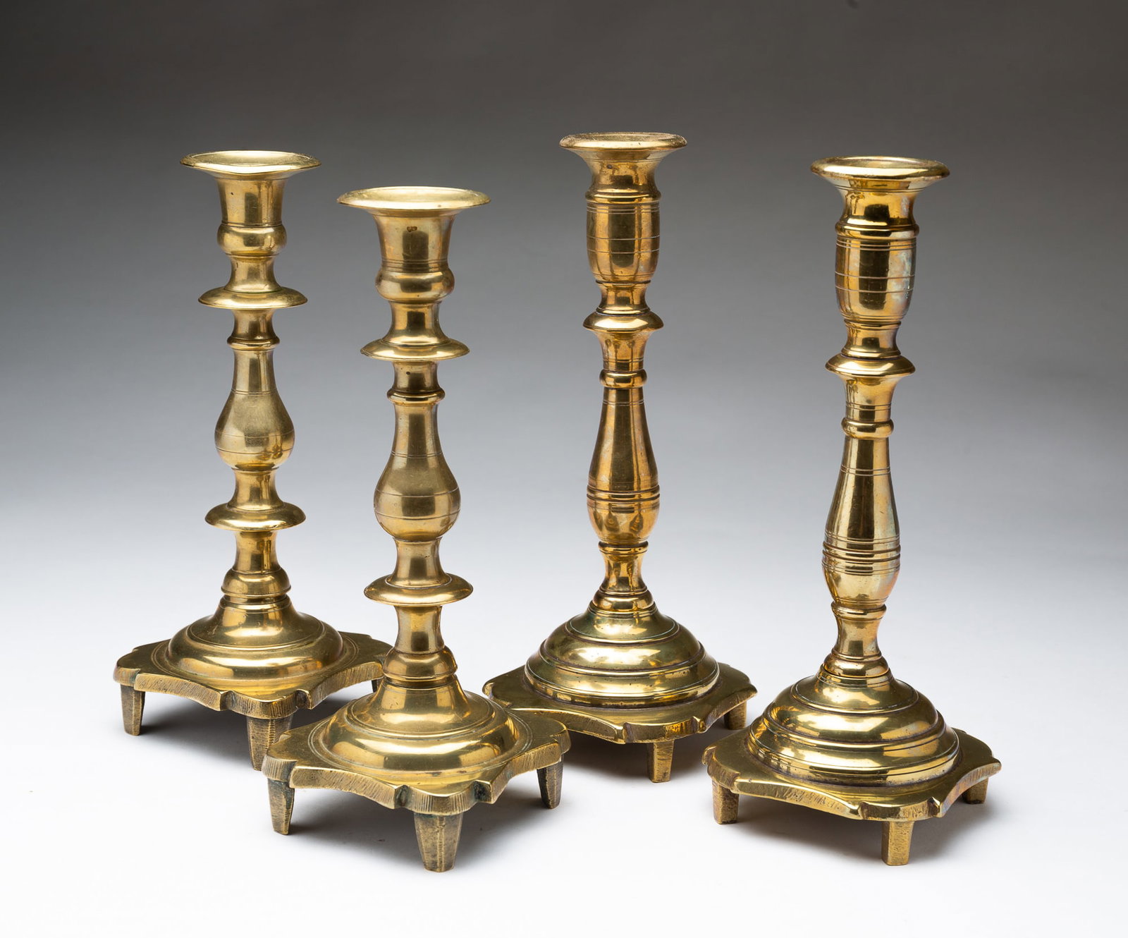 TWO PAIRS OF EASTERN EUROPEAN CAST BRASS CANDLESTICKS. (1 of 4)