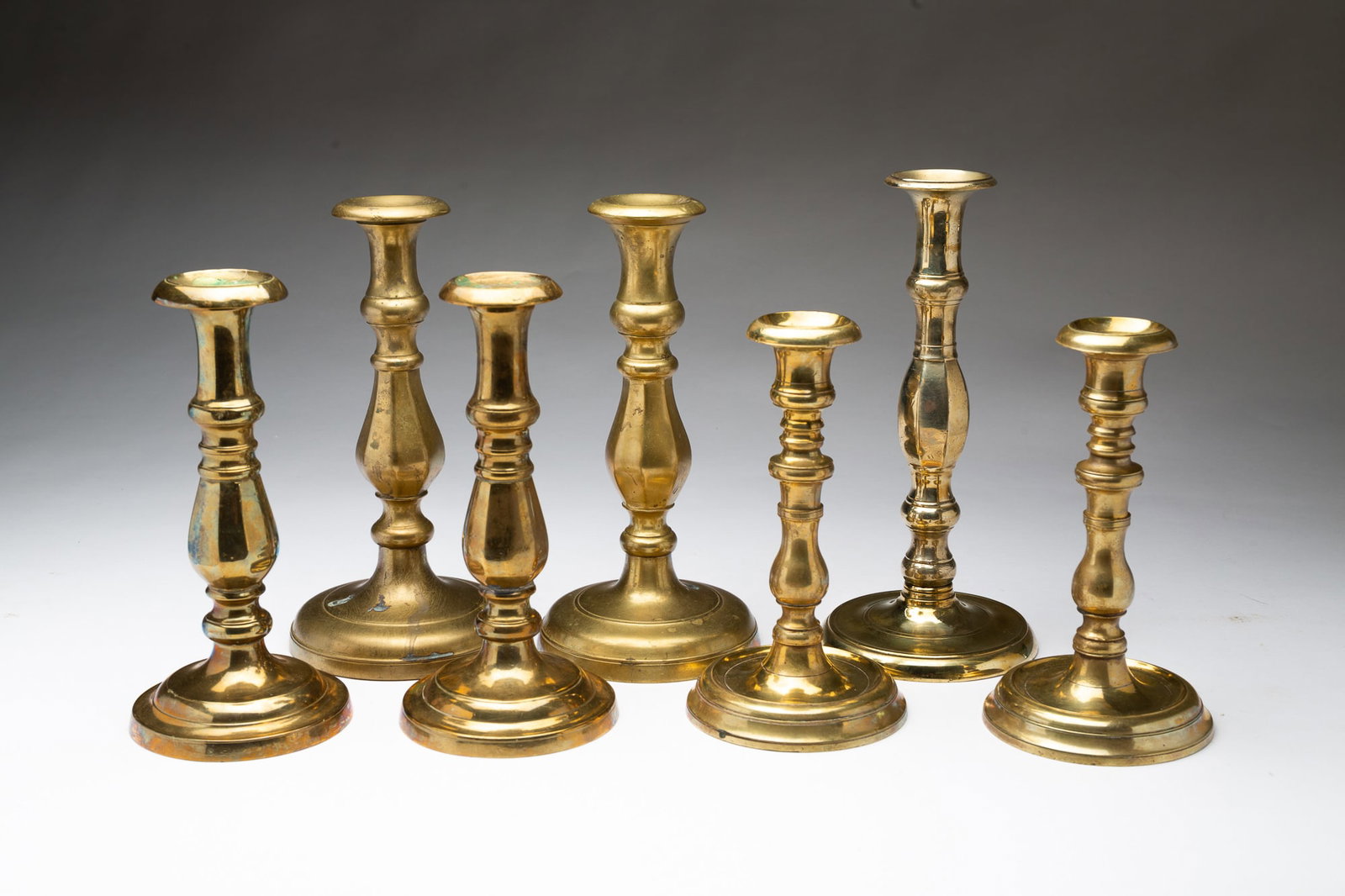 SEVEN EUROPEAN CAST BRASS CANDLESTICKS. (1 of 5)
