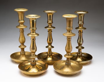 FIVE EUROPEAN CAST BRASS CANDLESTICKS.