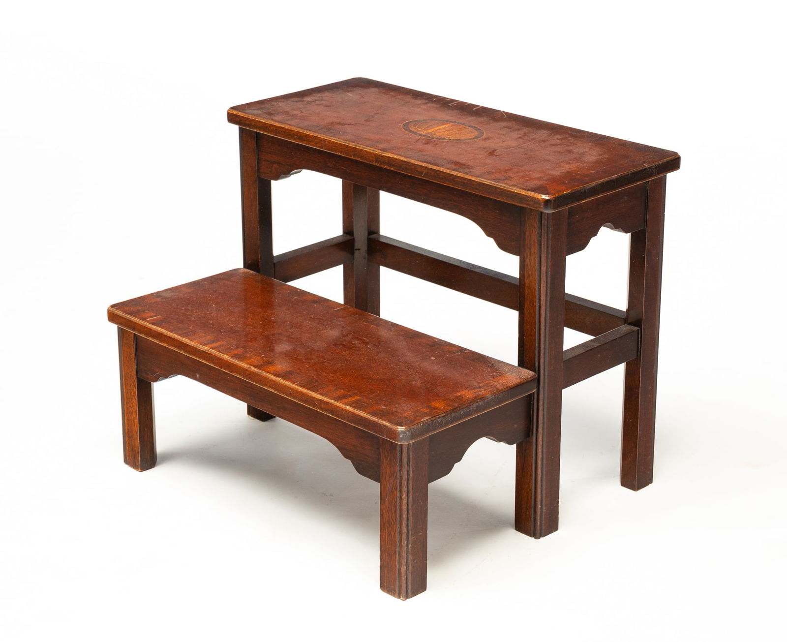 COUNCILL CRAFTSMAN (DENTON, NORTH CAROLINA) MAHOGANY AND MARQUETRY BED STEPS.: American, 20th Century. Mahogany and mahogany veneer. Two steps, the top with an oval shell marquetry inlay, shaped aprons, block legs, label on underside. 14"h. 18"w. 14.5"d.