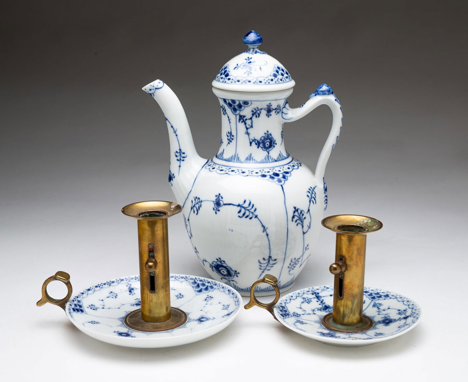TWO ROYAL COPENHAGEN BLUE FLUTED HALF LACE PORCELAIN CHAMBER STICKS AND A COFFEE POT.: Danish, 1970s. Two Blue Fluted Half Lace brass and porcelain push up chamber sticks, 4"h. and 4.5"h. Lidded coffee pot, 9.5"h. Each marked on underside. Three items total.