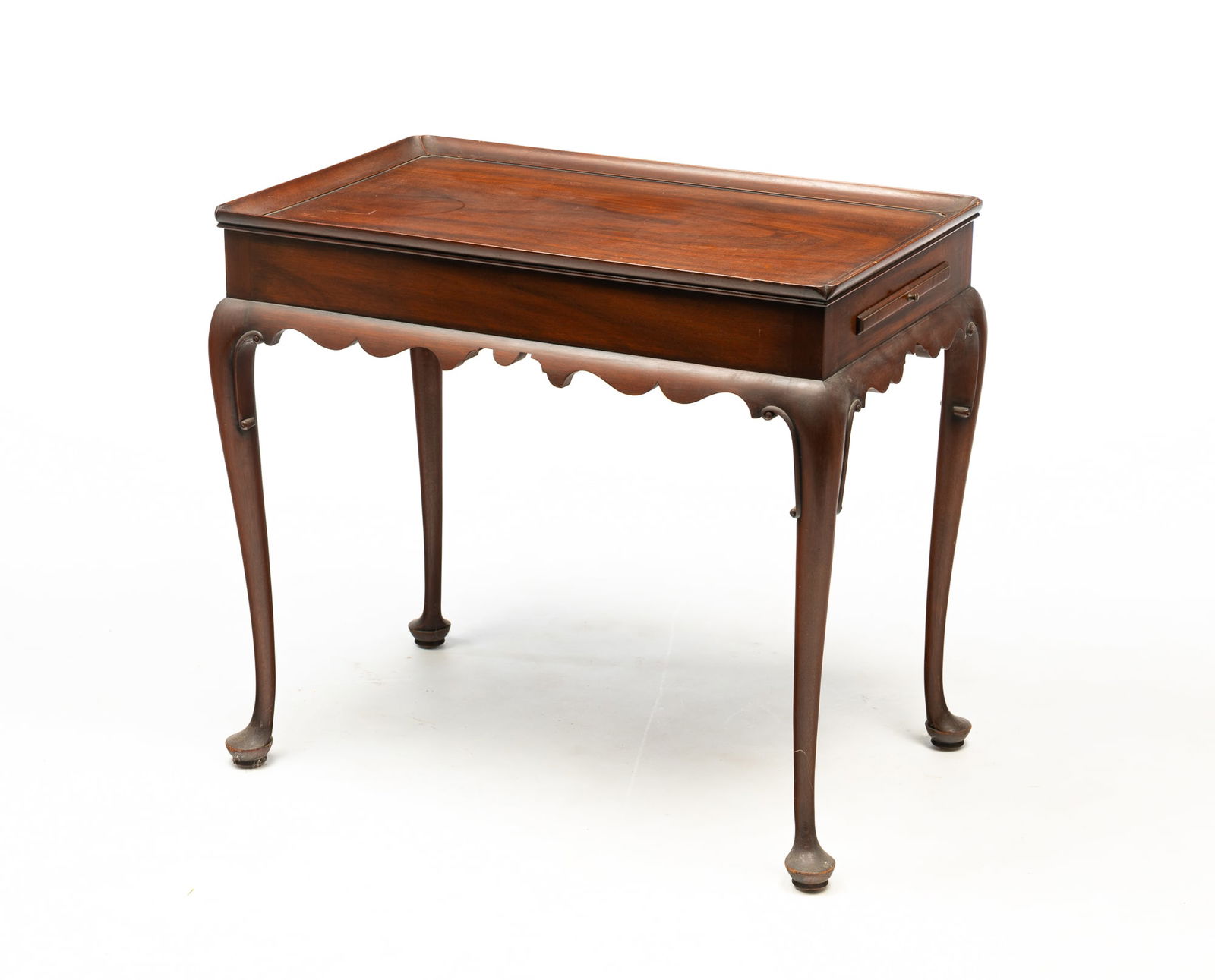 KITTINGER (BUFFALO, NEW YORK) "WILLIAMSBURG RESTORATION" QUEEN ANNE STYLE MAHOGANY TEA TABLE.: 20th Century. Having a rectangular, tray top above a conforming frieze with two pull-out candle slides over a scalloped apron and rising on cabriole legs ending in pad feet. 26.25"h. 18.75"w. 30.25"d.