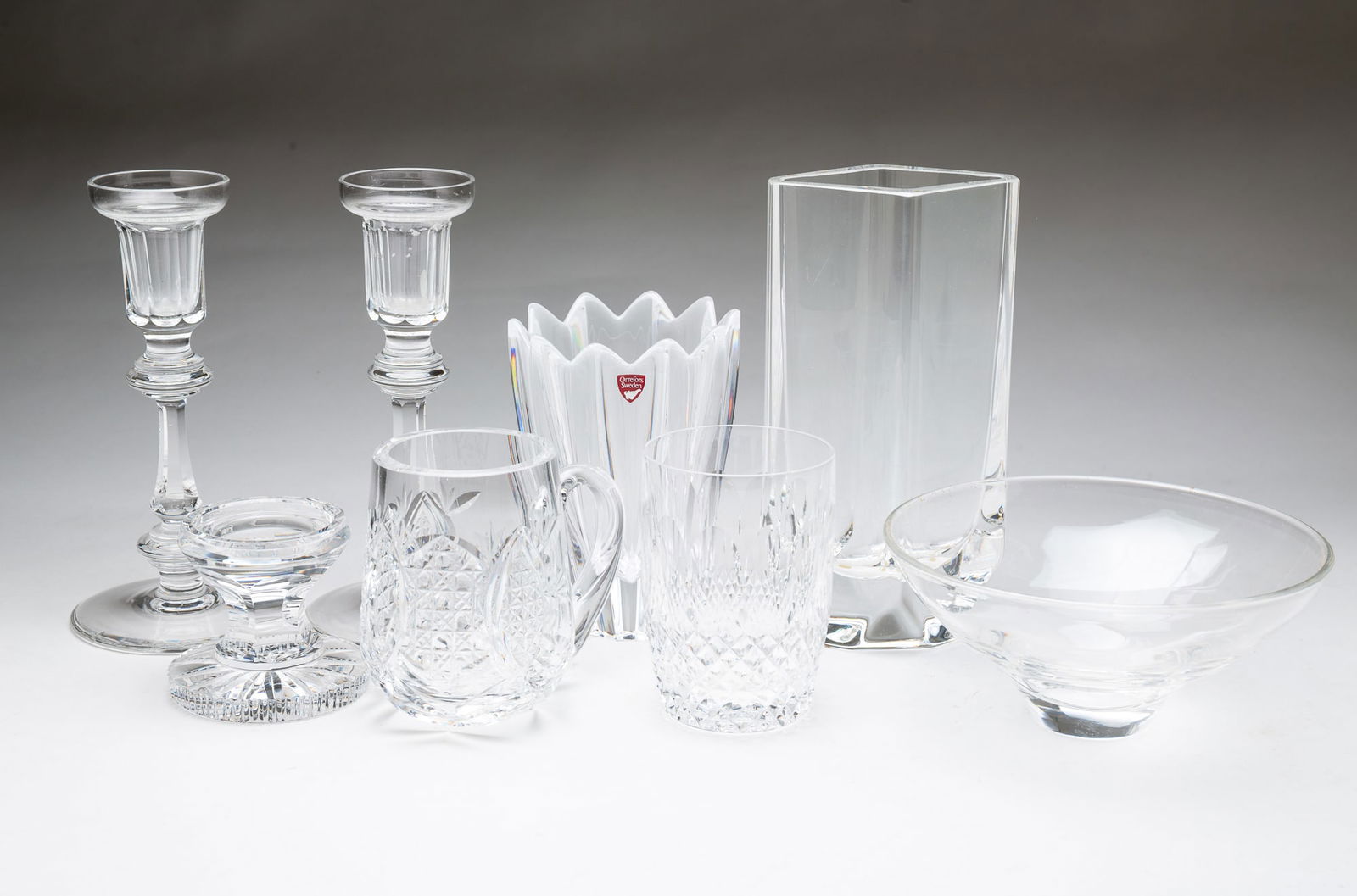 EIGHT CLEAR CRYSTAL ITEMS, INCL. WATERFORD AND ORREFORS.: Late 20th Century. Five are Irish Waterford: a pair of candlesticks, 8.25"h., a tumbler, 4.15"h., a mug, 4.5"h., and a low candlestick, 3"h. Two are Swedish: a panel-cut vase by Kosta, 8.25"h., and
