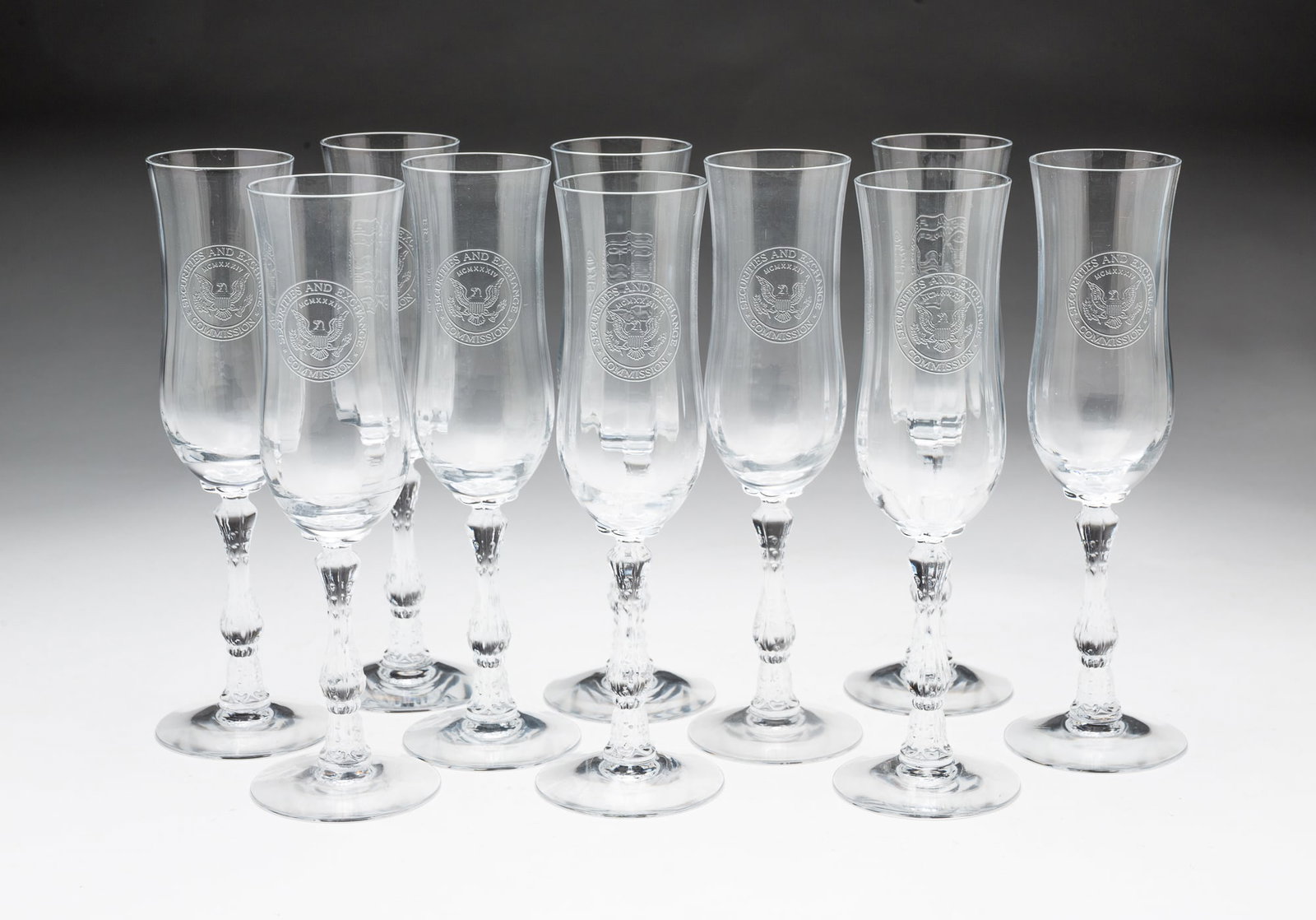 TEN FOSTORIA GLASS COMPANY (FOSTORIA, OHIO) SECURITIES AND EXCHANGE COMMISSION CHAMPAGNE FLUTES,: American. Fluted body with engraving, shaped stem, and acid etched mark to bottom. 8"h.