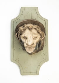 CAST CONCRETE LION'S MASK ON WOOD PLAQUE.