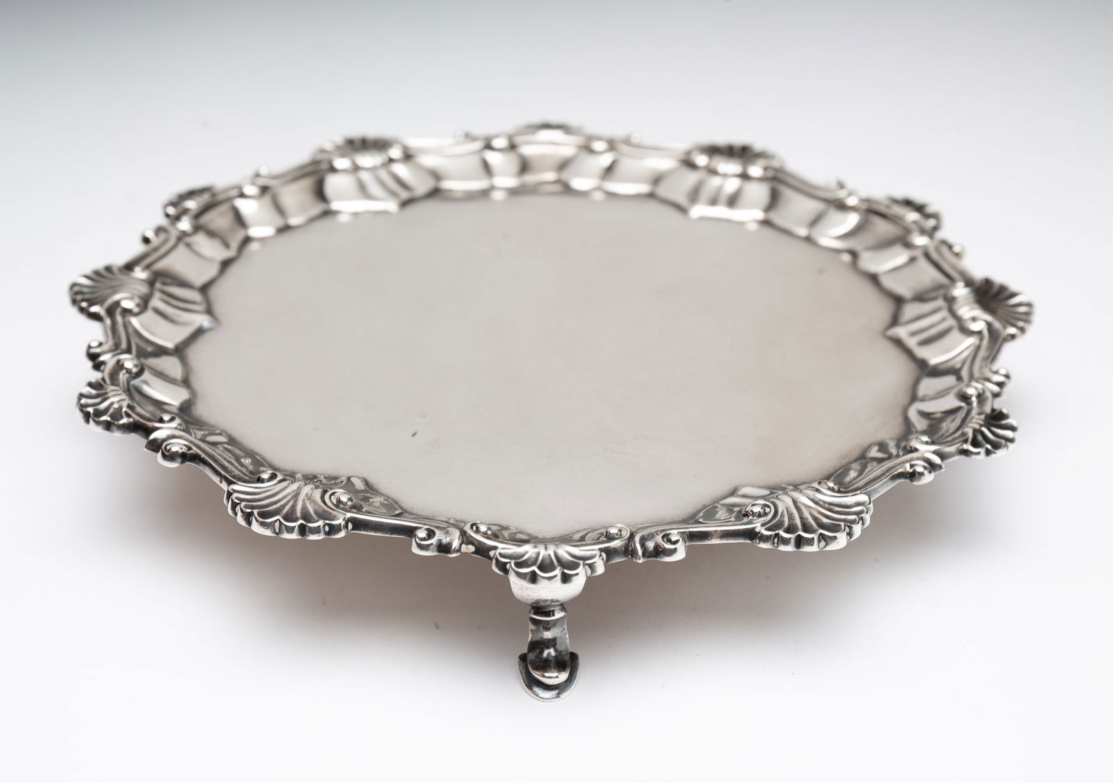 ENGLISH STERLING SILVER FOOTED SALVER.: London, with date mark for 1743-64. Shell and leaf bracket border with shaped legs and pad feet. E.C in a rectangle maker’s mark. 1”h. 7.5"d. Approx. 8.5”d.