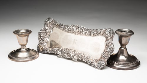 TWO AMERICAN WEIGHTED STERLING SILVER CANDLESTICKS AND A REPOUSSE TRAY.