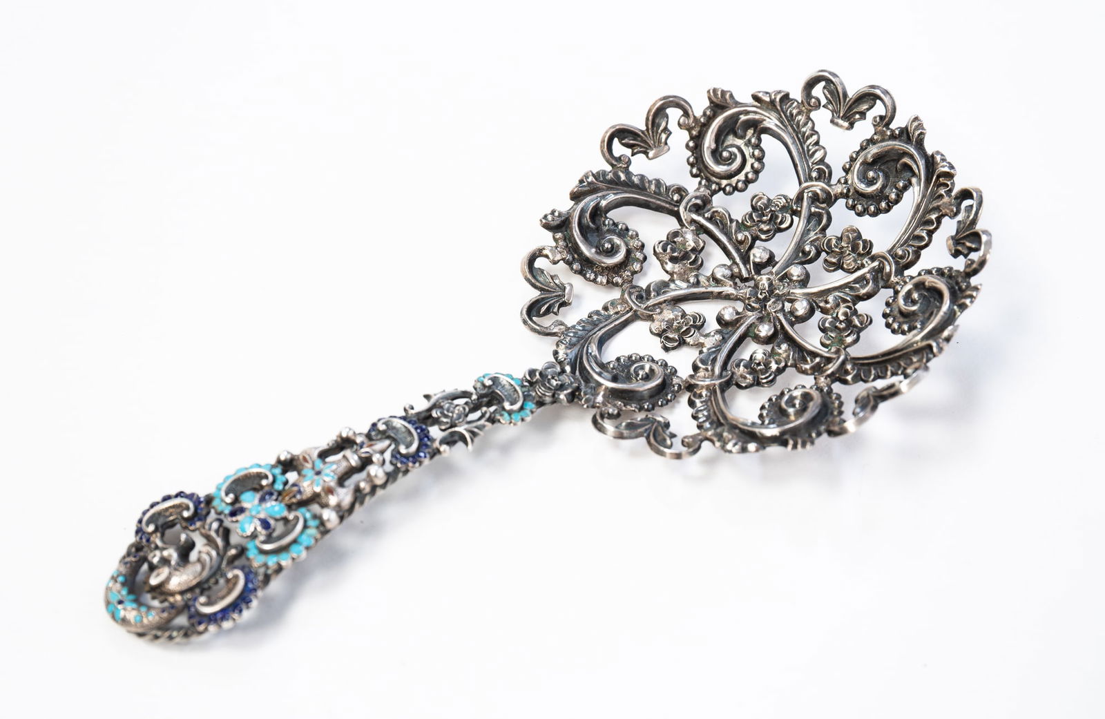VICTORIAN STERLING SILVER AND ENAMEL BON BON SERVING SPOON.: Second half 19th Century. Floral and foliate reticulated bowl and handle. Handle with turquoise, cobalt blue and amber colored enamel. Marked "STERLING" on back of handle near bowl. Approximately 1.4