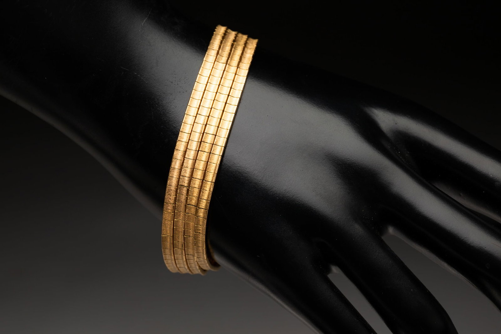 18K YELLOW GOLD MULTI-STRAND BRACELET.: Contemporary 18k gold. Marked '750'. Four articulated strands attached with tab closure and safety catch. 7.5"l. Approximately 39.2g. **Note: Bidders who are not yet established with our firm will be