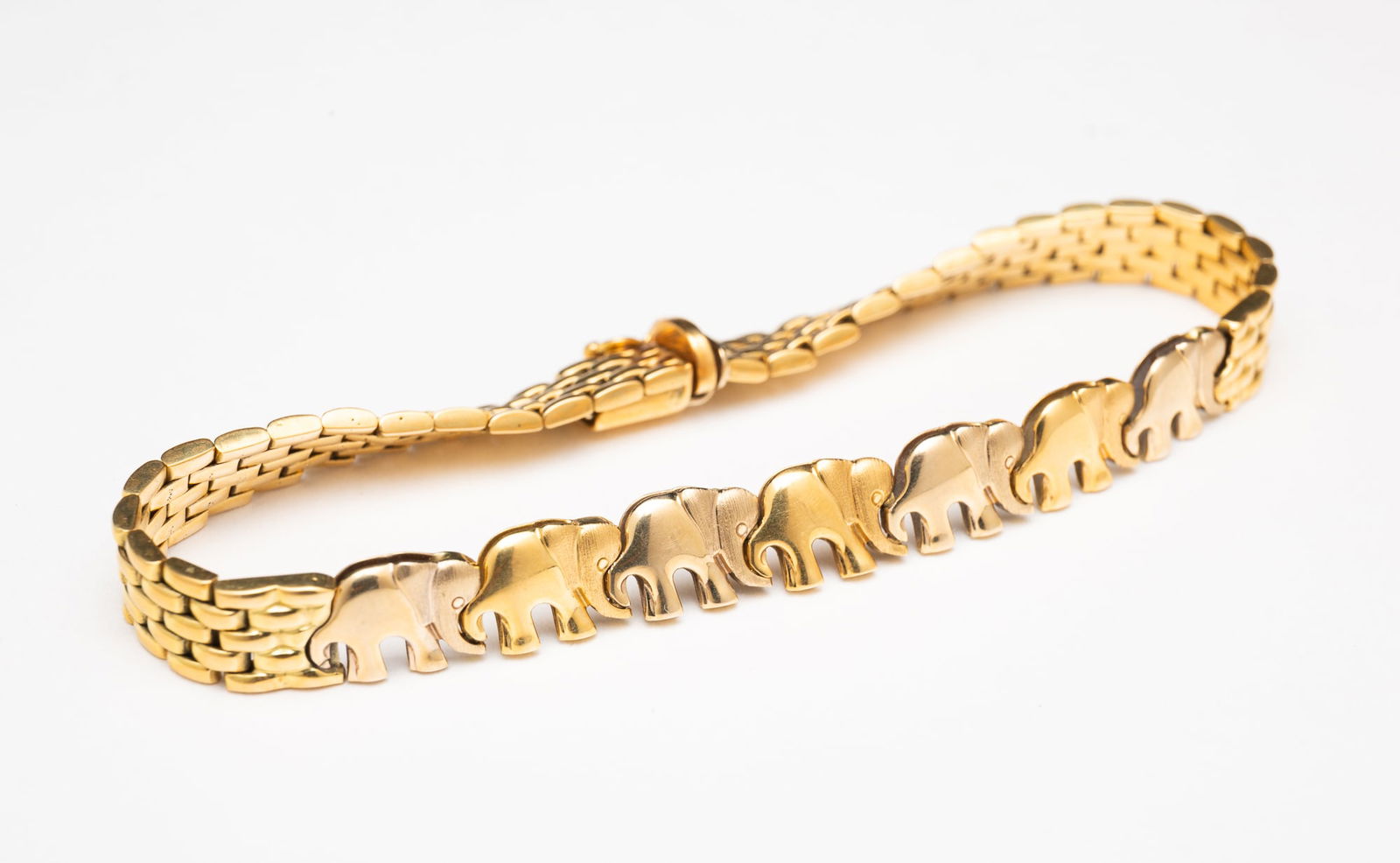18K YELLOW GOLD ELEPHANT BRACELET.: Contemporary. Fancy link bracelet with seven joind elephants to middine with box tab clasp. 7.25"l. Approximately 19.8 g.