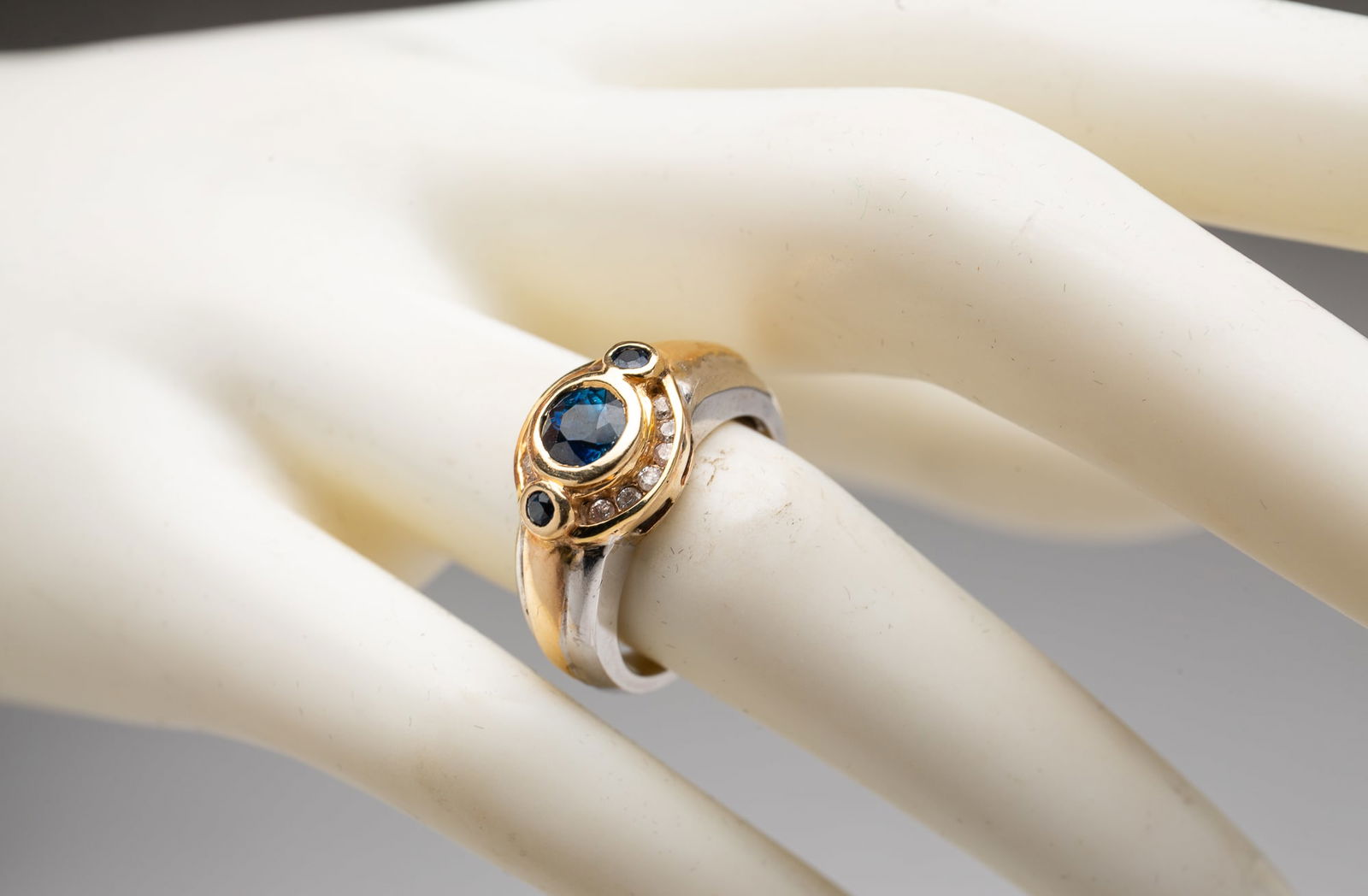 14K TWO TONE DIAMOND AND GEMSTONE RING.: Contemporary. Having twelve small round diamonds and three dark blue-green stones. Approximately 6.7g. Ring size 5.75.