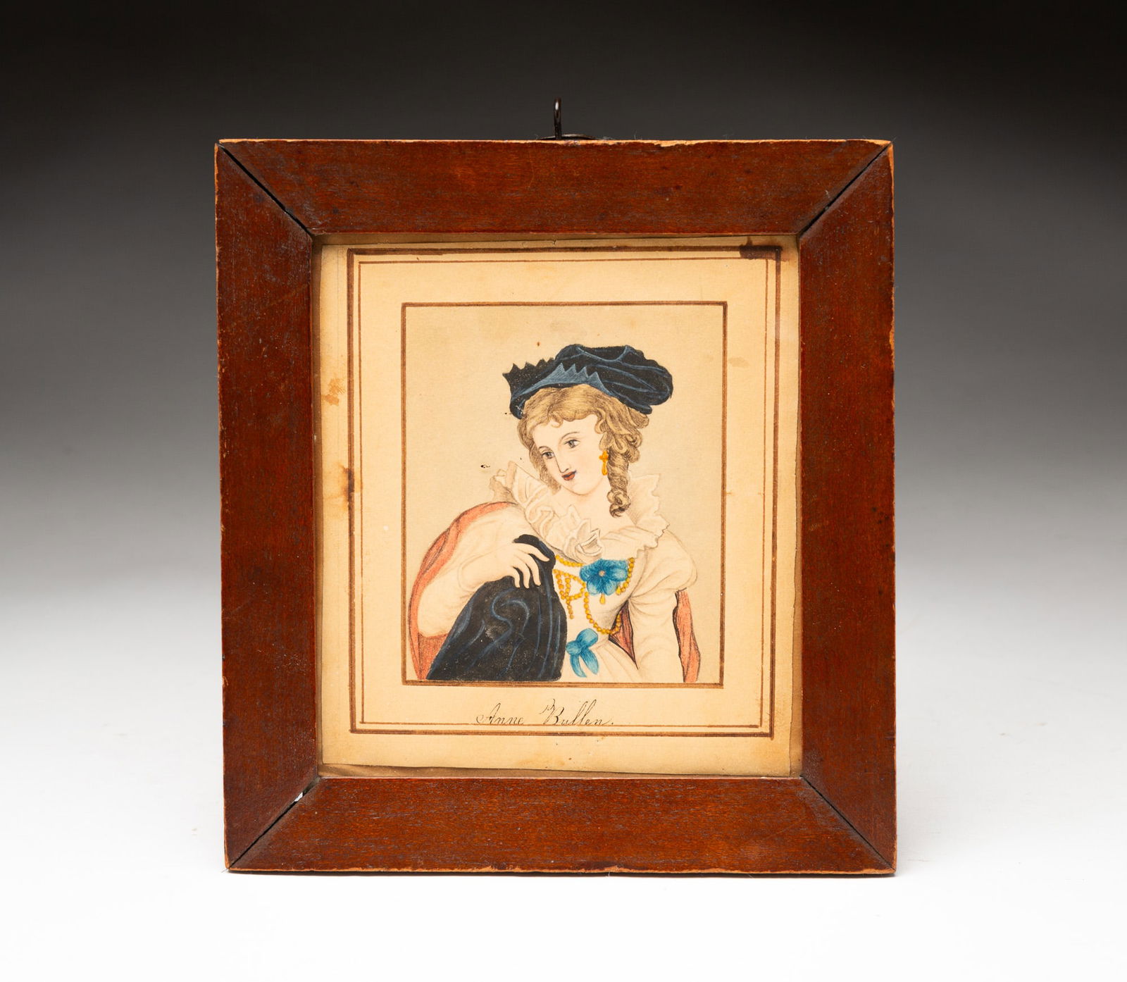 ENGLISH SCHOOL FOLK ART WATERCOLOR PORTRAIT OF ANNE BULLEN (ANNE BOLEYN).: 19th Century. On paper. Image of the young Queen of England and wife of Henry VIII wearing a blue hat, a white dress with ruffled collar, and a red cape; her hair in curls; inscribed "Anne Bullen" at