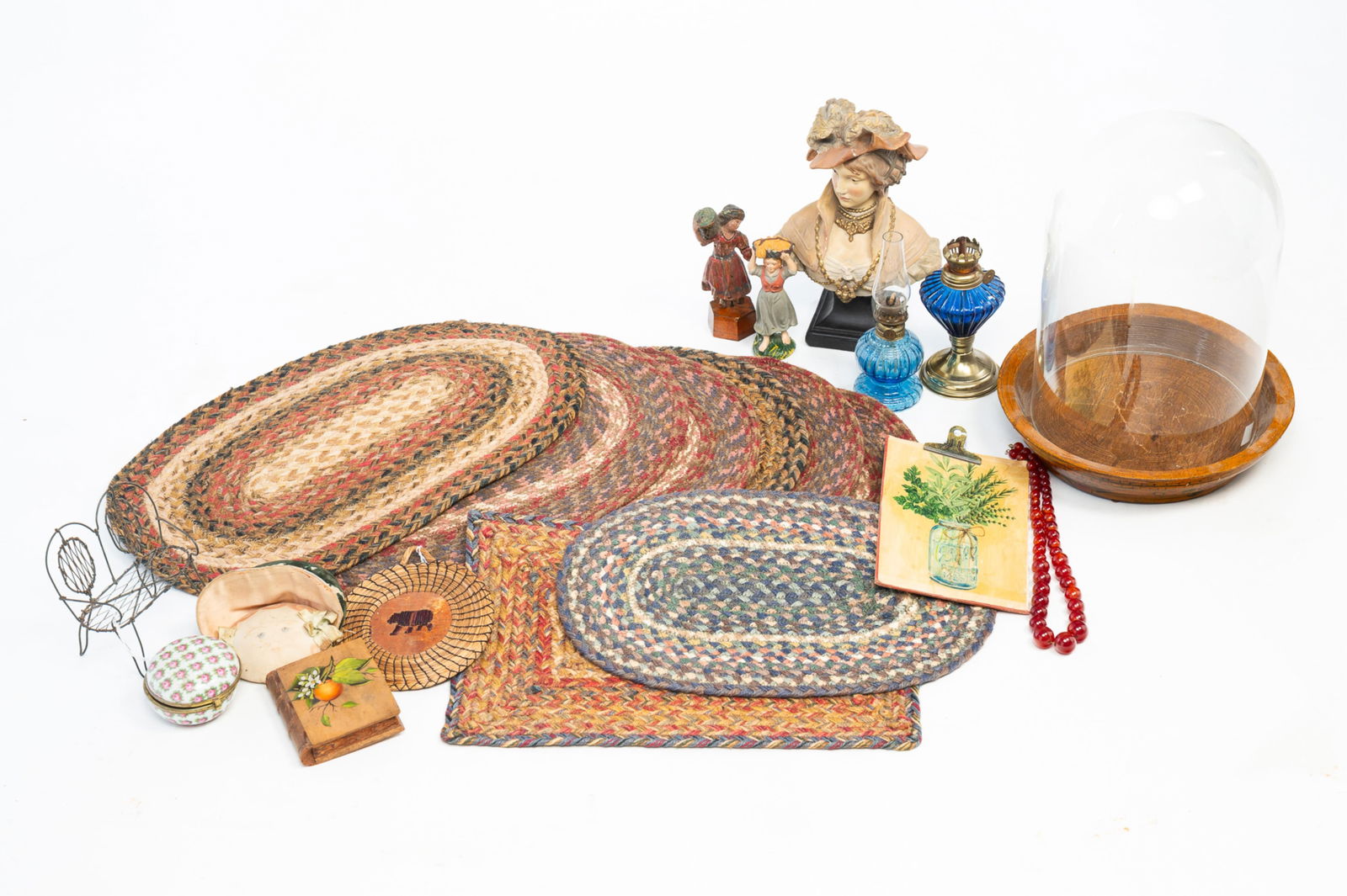 ECLECTIC GROUP OF HOUSEHOLD OBJECTS, INCL. EIGHT BRAIDED-COTTON PLACEMATS.: 19th-20th Century. Painted plaster bust of a woman wearing fancy attire; carved and painted figurine of a woman carrying a basket on her head; Czech round porcelain jewel box; grass and birch bark
