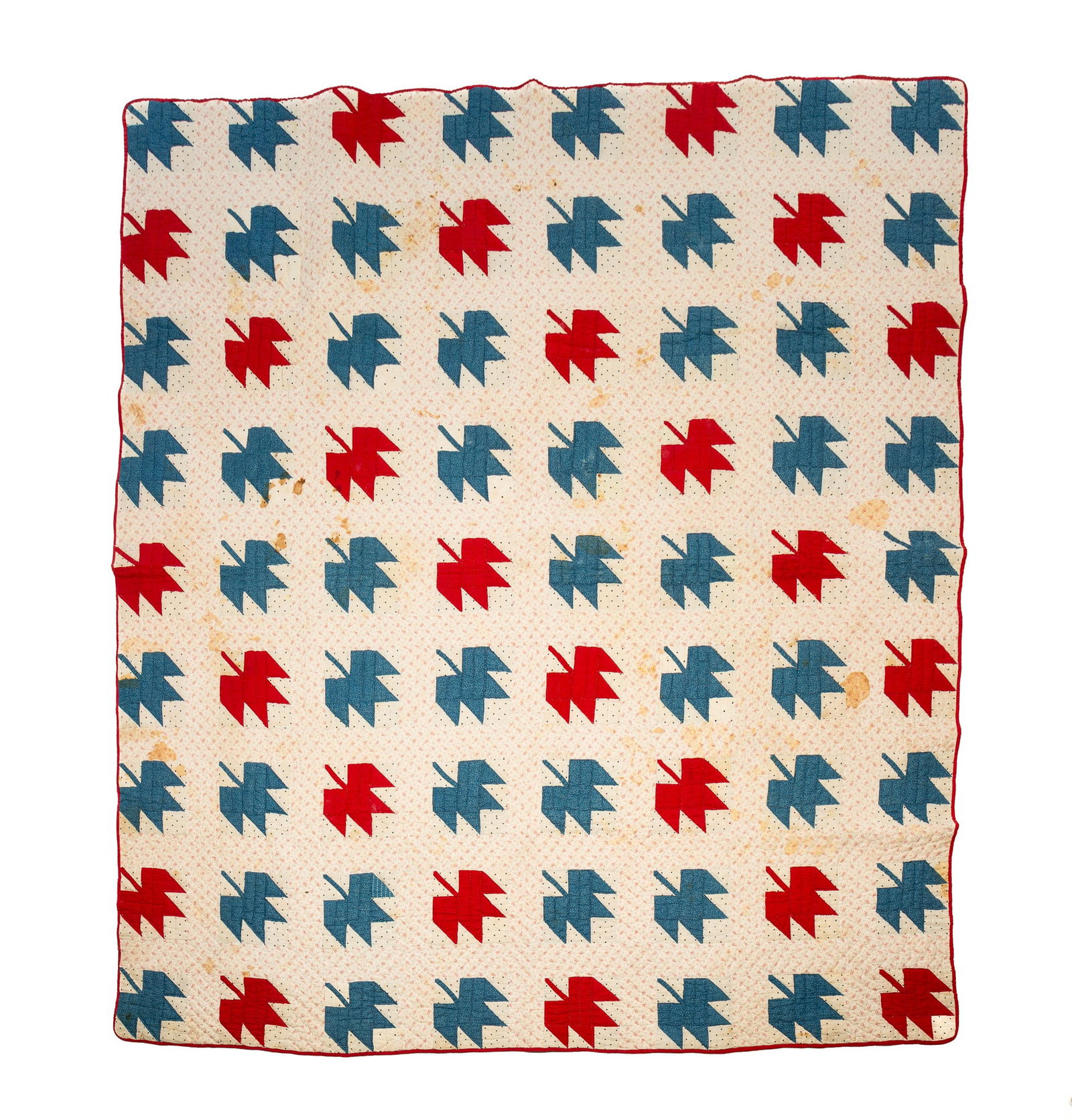 AMERICAN COTTON MAPLE LEAF QUILT.: First half 20th Century. Hand-stitched. Patterned white fabric background with patterned blue and solid red maple leaves.Provenance: From the Lifetime Quilt and Textile Collection of Louise A.