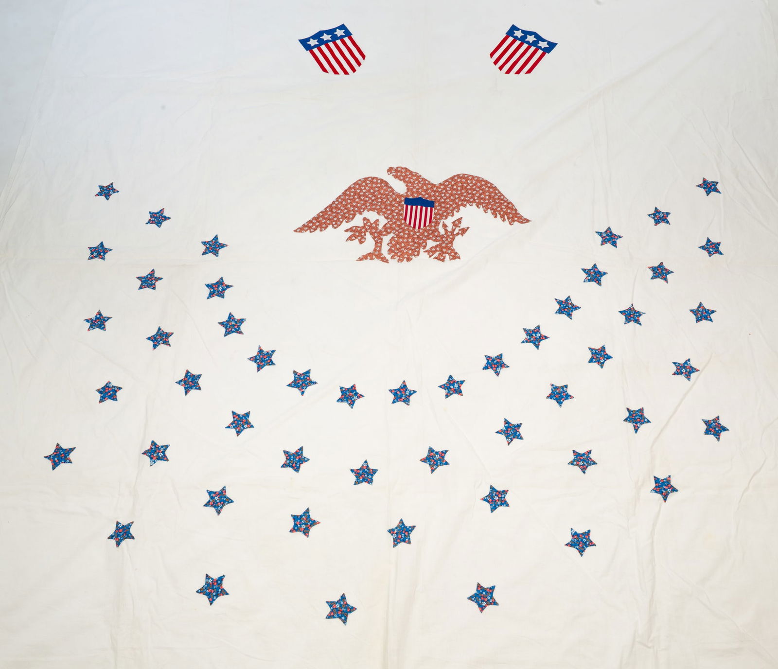 TWO AMERICAN COTTON APPLIQUE PATRIOTIC BED SHEETS.: Second half 20th Century. Hand-stitched applique stars, U.S. Shields, and a shield-breasted, spread-wing eagle.Provenance: From the Lifetime Quilt and Textile Collection of Louise A. Veninga (Santa