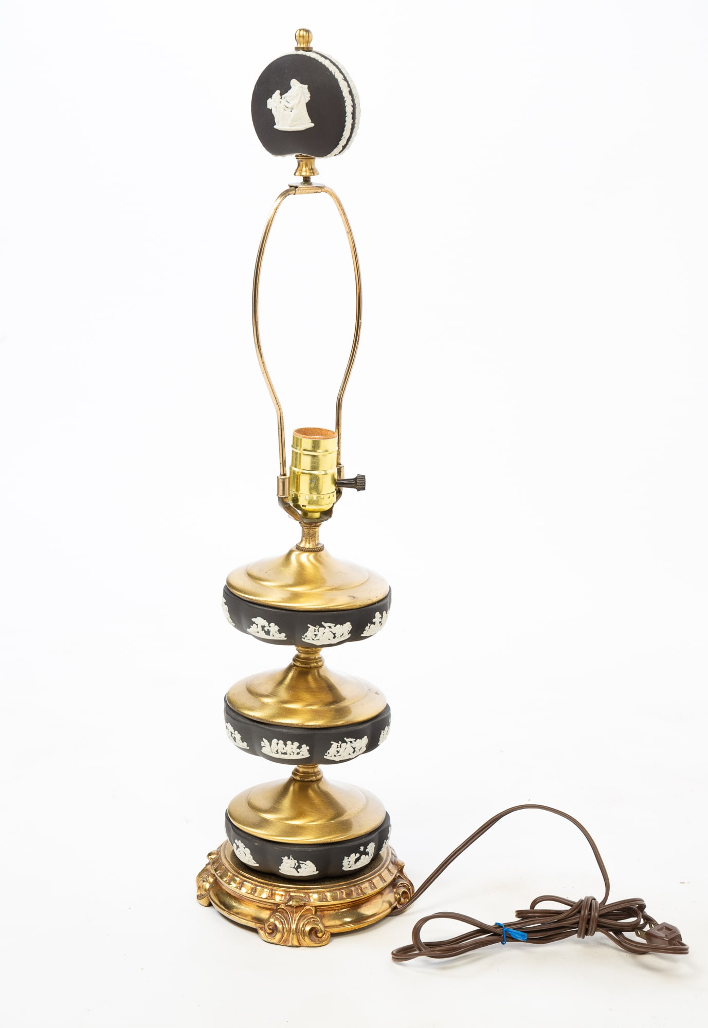 WEDGWOOD STYLE JASPERWARE AND BRASS TABLE LAMP.: English, 20th Century. Three black Jasperware discs depicting angels and putti on a brass standard with a single light socket, harp, and a Jasperware finial, on a circular base decorated with