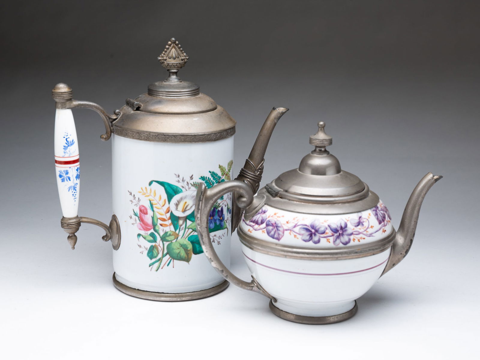 TWO ENGLISH ENAMELED COFFEE POTS.: Late 19th Century. White enamel with floral decoration and white metal mounts. 10.5"h. and 7.5"h.