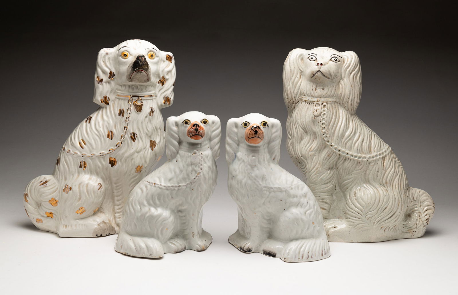 FOUR STAFFORDSHIRE SPANIELS.: English, Second half 19th Century. All four are white with gold decoration comprising two smaller examples and two larger dogs, one with gold spots. Two smaller 9.25"h. and 9.5"h. Single with gold