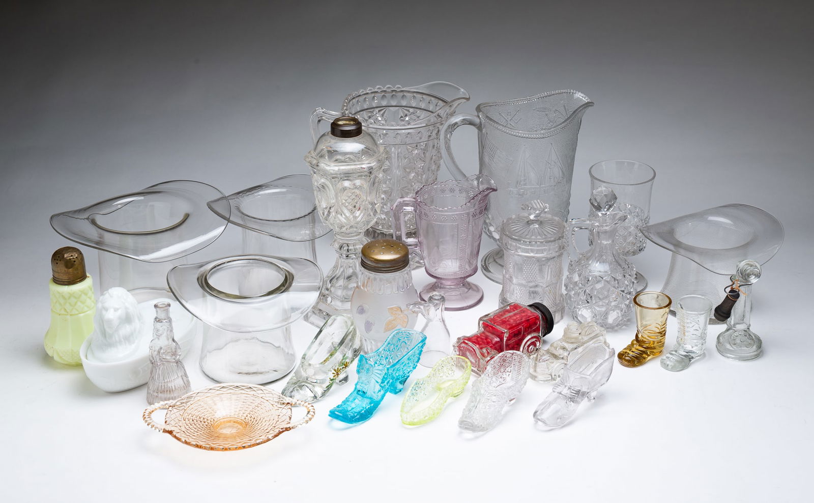 GROUP OF AMERICAN PRESSED GLASS.: Late 19th-20th Century. Included are top hats, pitchers, slippers, a milk glass "British Won" covered dish, a candy container, creamers, and other items. From 1"h. to 10"h.