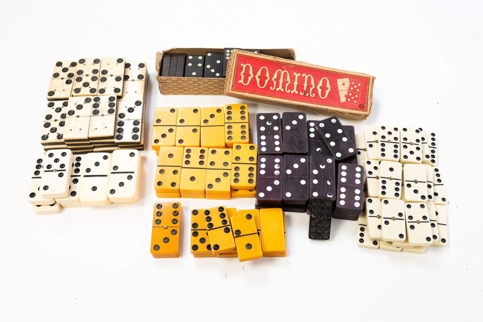 LARGE COLLECTION OF DOMINOES INCLUDING BAKELITE.: American, 20th Century. Includes dominoes in various sizes and thicknesses. In a variety of materials, including Bakelite, bone, and wood. Domino box 1.25"h. 6.25"w. 2"d.