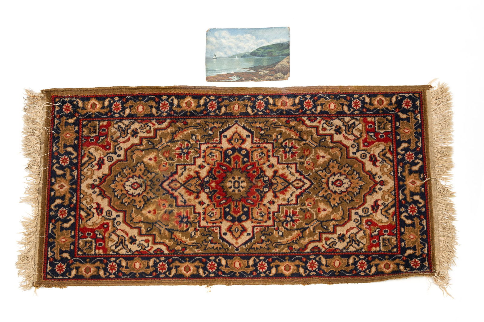 SMALL OIL ON BOARD SEASCAPE AND A MACHINE-MADE AREA RUG.: 20th Century. An American oil on artist's board of a rocky shoreline with hilly background and sailboats. And a rug with gold field and floral and geometric pattern. Painting 7"h. 10"w. Rug, 2'w. 3'10