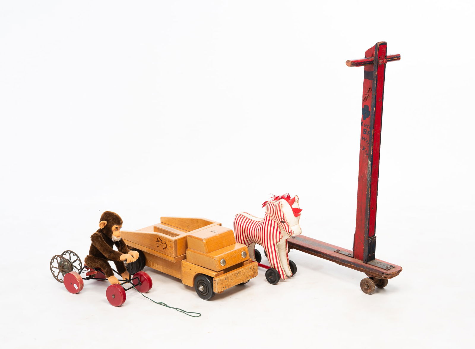 GROUP OF FIVE TOYS WITH WHEELS.: American and German, Mid-20th Century. Comprising a Community wood truck, a red-and-white stuffed zebra, a Steiff monkey pull toy, a bell with iron heart-decorated wheels, and a handmade painted wood