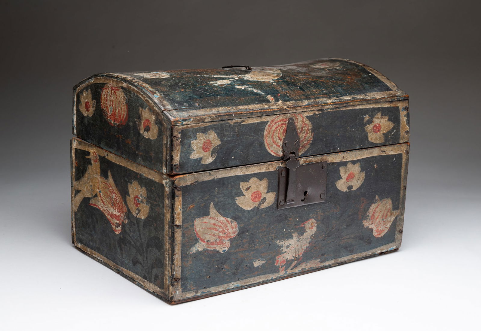 EUROPEAN FOLK ART POLYCHROME-DECORATED BEECH DOME-TOP BOX.: 19th Century. Having a rectangular, domed lid with wire bail handle and wire hinges above a conforming case. The exterior decorated with stylized flowers and birds. The front is fitted with an iron ha