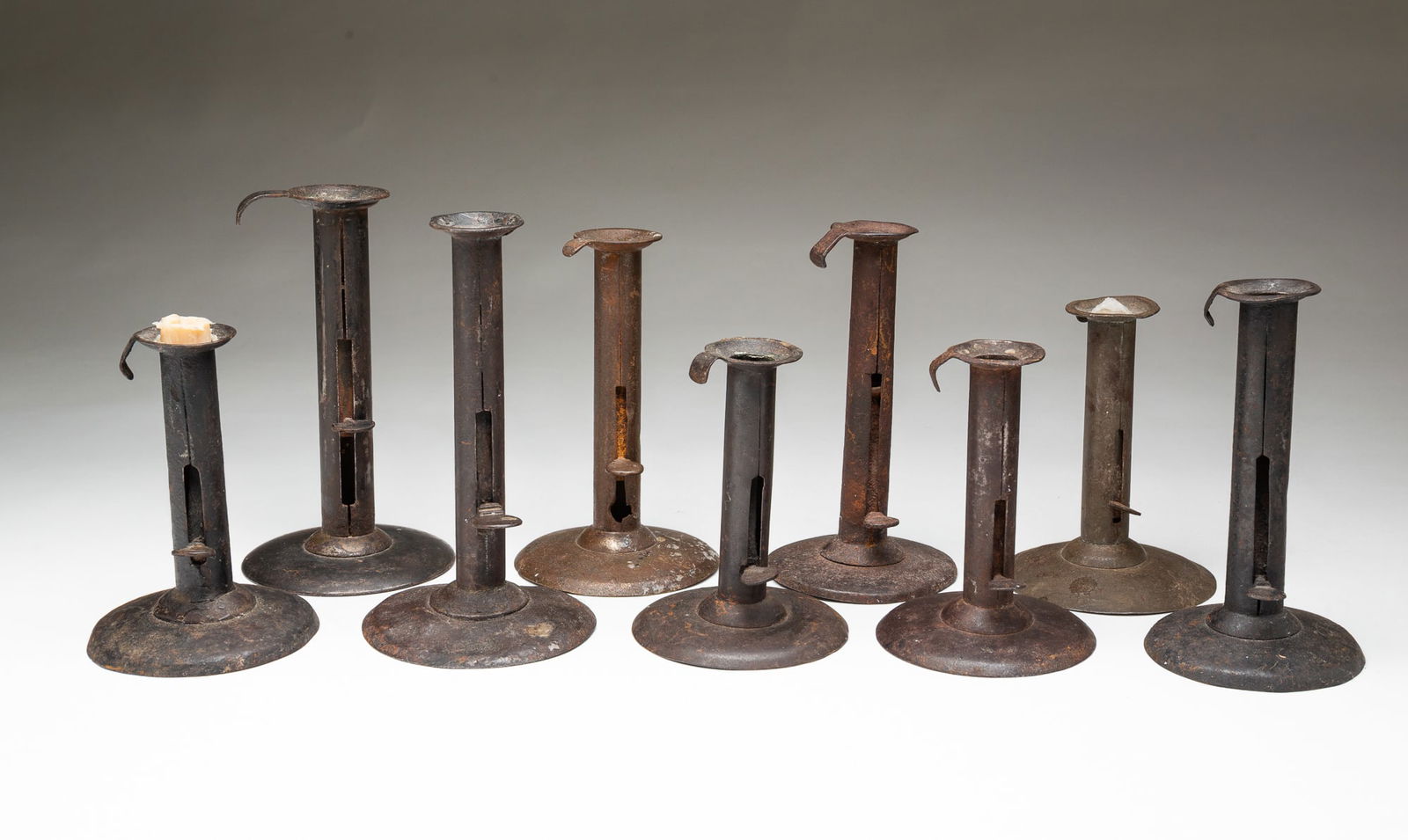 NINE HOGSCRAPER CANDLESTICKS. From 7.5"h. to 5.25"h. (1 of 5)